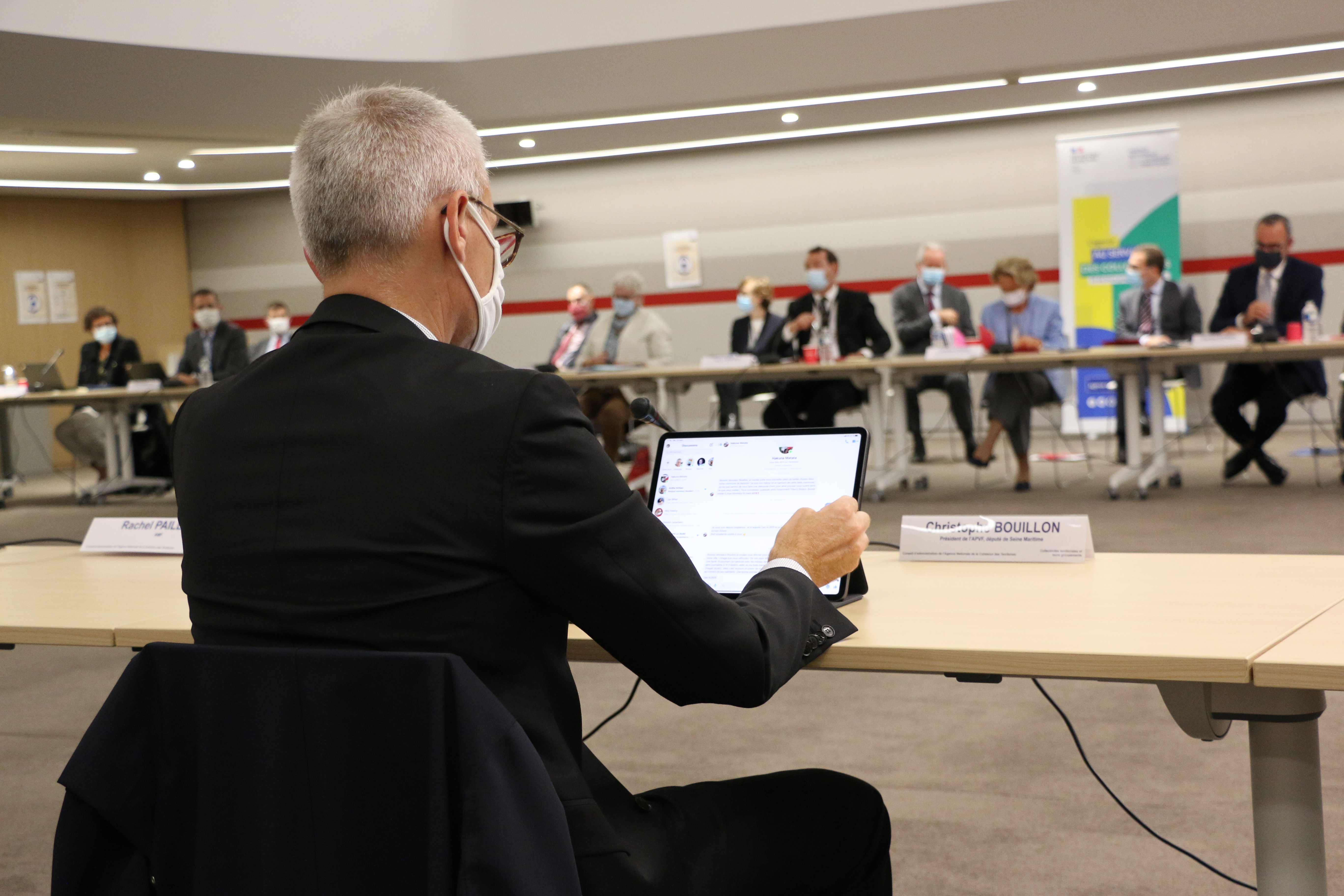 Vue large de la r&eacute;union du conseil d'adminstration, avec une personne de dos et son ordinateur au 1er plan