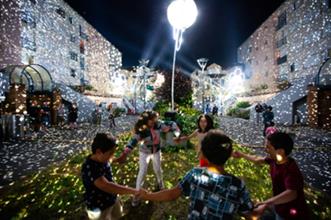 Projection de lumières sur des immeubles, avec des enfants qui font une ronde au 1er plan