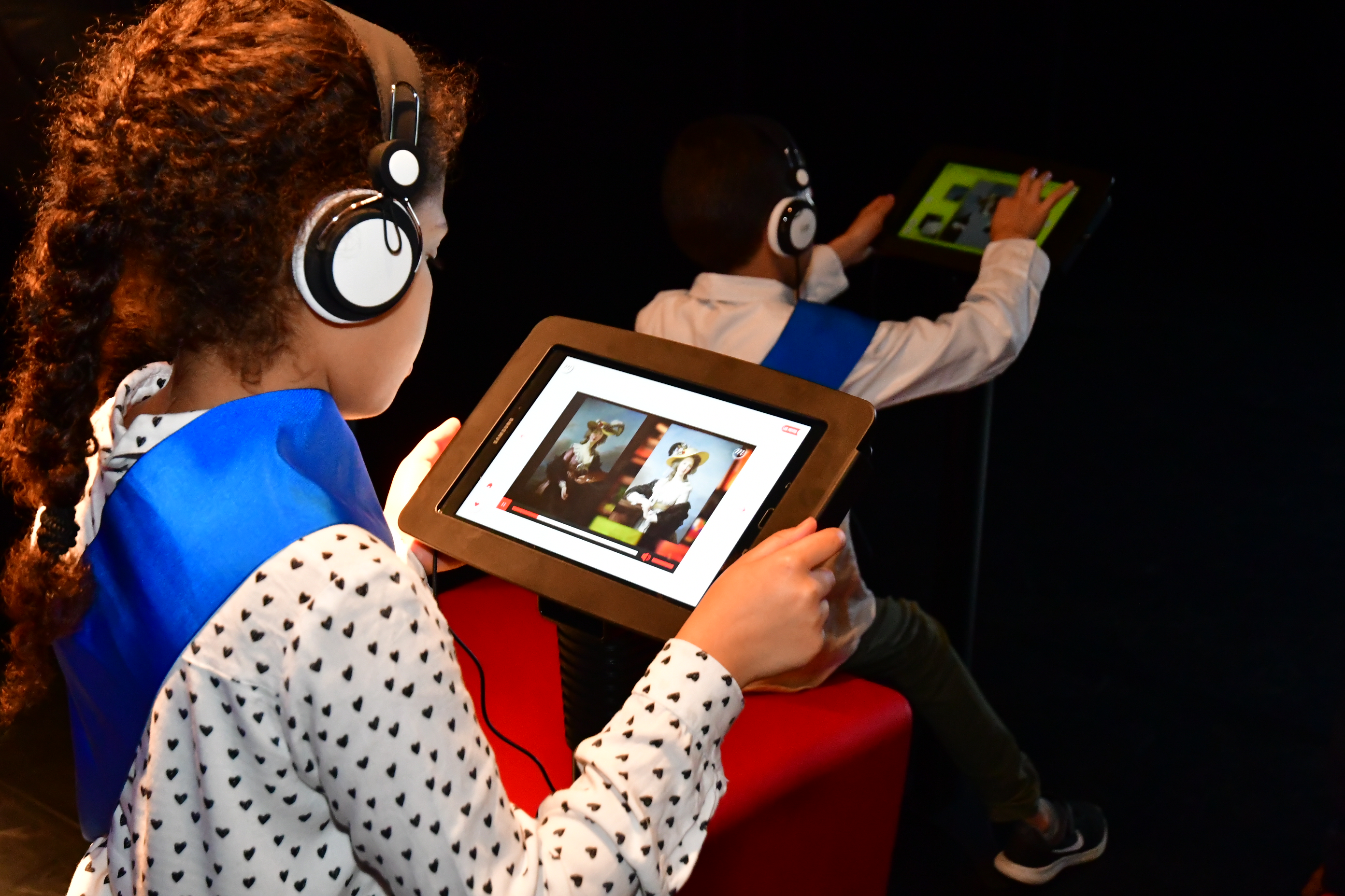 Une enfant de la ville des Mureaux (78) d&eacute;couvre des oeuvres d'art num&eacute;ris&eacute;es sur une tablle. Elle &eacute;coute le commentaire avec le casque. 