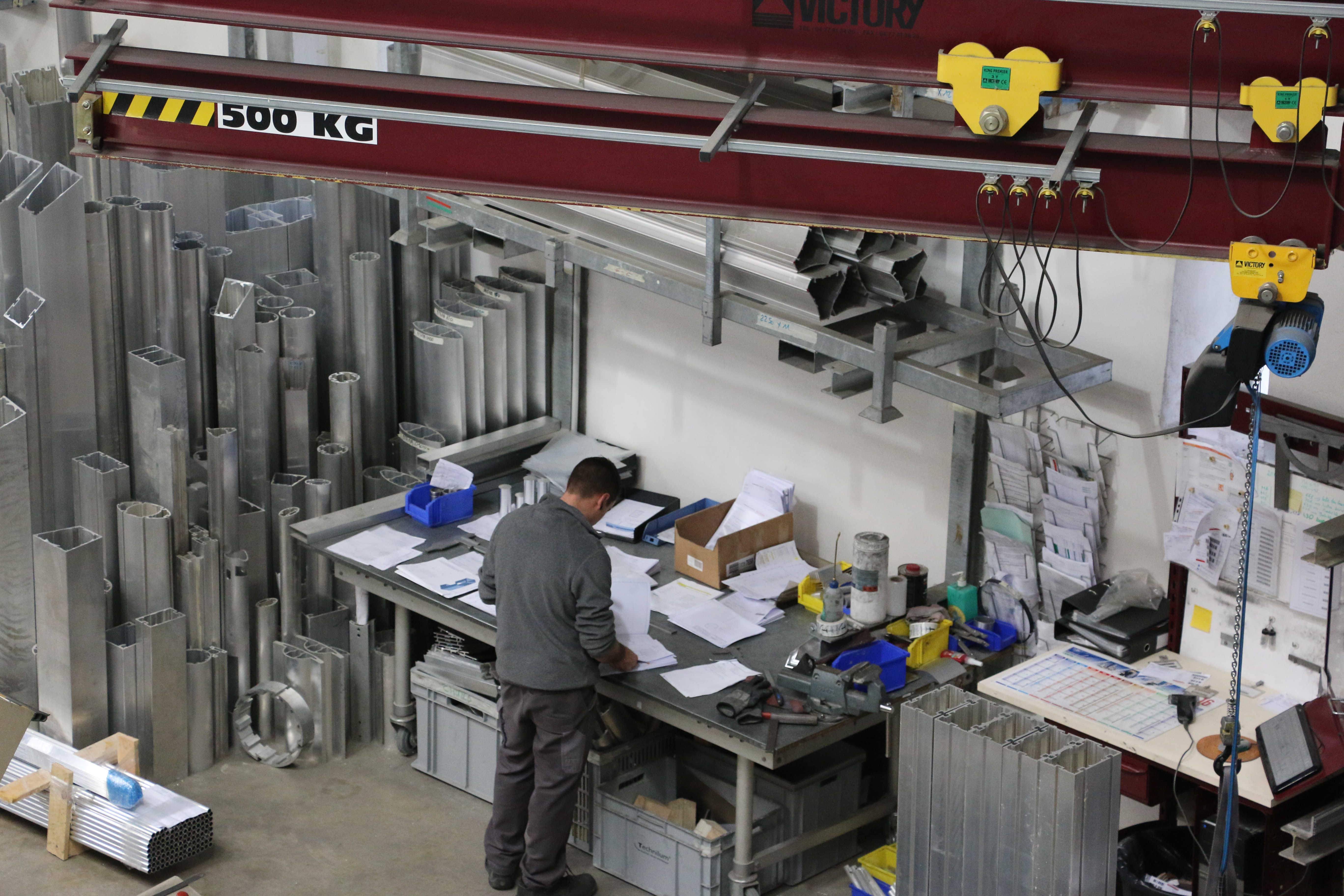 Vue en contre-plong&eacute;e d'un atelier de faricaiton de pyl&ocirc;nes &eacute;lectriques avec un ouvrier &agrave; son &eacute;tablit