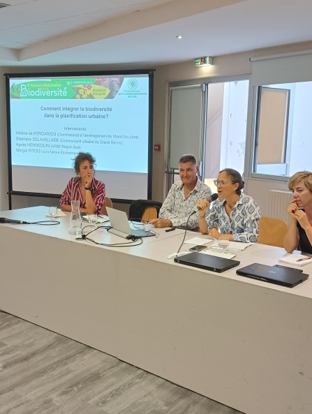 4 personnes assises le long d'une table en long, avec un écran lumineux au bout.