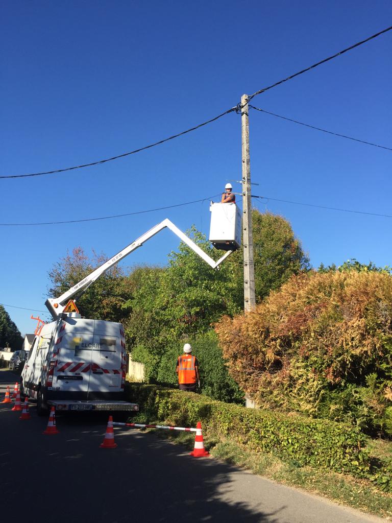 Su une route de campagne, un homme dans une nacelle en hauteur pose la fibre optique sur un poteau &eacute;lectrique d&eacute;j&agrave; pr&eacute;sent. 