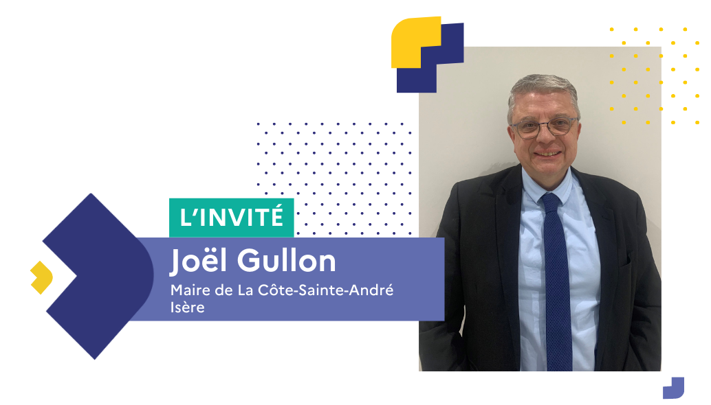 Portrait en buste de Joël Gullon, en cosutme, chemise et cravate bleus, cheveux courts gris et lunettes.