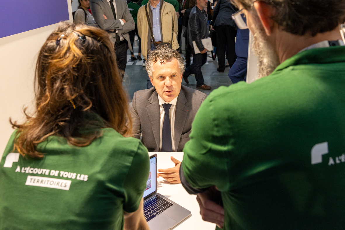 Le ministre C. B&eacute;chu discute avec deus agents de l'ANCT de dos, avec leurs t-shirt vert.