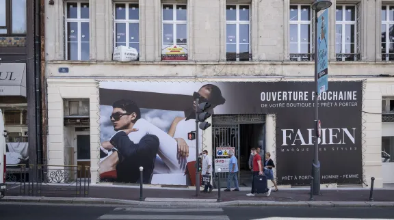 Dans une rue de St-Quentin, dans le Nord, des passants devant une nouvelle boutique qui affiche l'annonce de son ouverture pochaine.