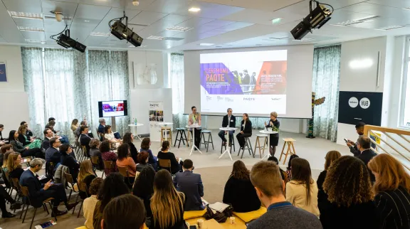 Vue de persones assises en demi-lune dans une grande salle, devant un grand &eacute;cran aux couleurs de la c&eacute;r&eacute;onie